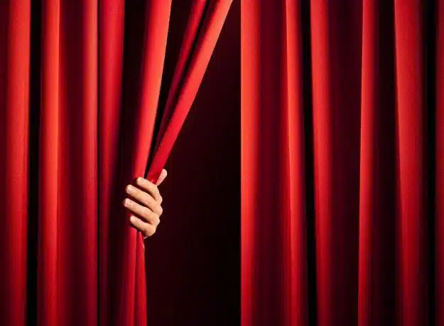 male hand in the act of disclose the scene shifting the red curtain Atelier teambuilding developement personnel théâtre Impro pour seminaire, workshop